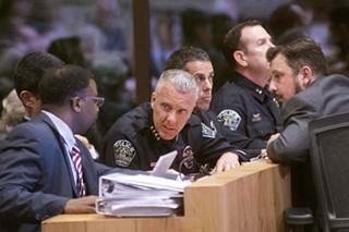 Assistant City Managers Mark Washington and Rey Arellano (hidden) talk with Police Chief Brian Manley during Wednesday’s specially called City Council meeting.