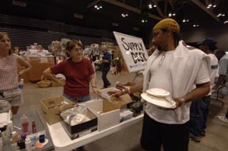 A Katrina evacuee scans tables for needed living supplies as 
he tries to assemble a life at the Austin Convention Center.