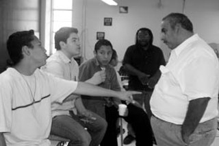 Eduardo Sifuentes, Luis Miguel Orozco, and German Sifuentes discuss politics with Alfredo Santos. Tim Eubanks of Austin Voices for Education and Youth stands in the background.
