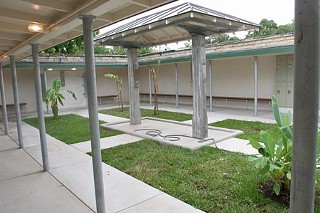 Restored men’s changing area, showing the open roof, shaded wall benches, and central showering area, and landscaping.