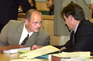 Attorney Steve Edwards (r) consults with his client, former APD Officer Eric Snyder, during their attempt to prove that APD selectively punishes officers accused of wrongdoing.